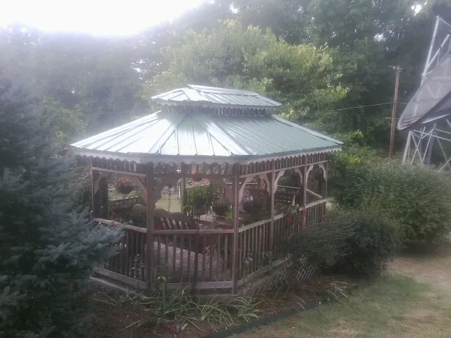 Green metal roof on a backyard gazebo surrounded by garden beds in Albany